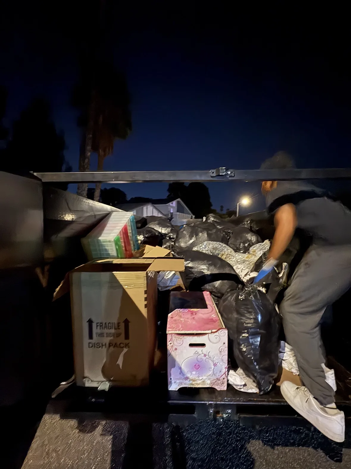 Crew loading backyard debris into a trailer at night
